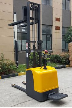 a yellow and black forklift parked in front of a building