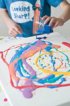 a young boy is painting with colorful paint