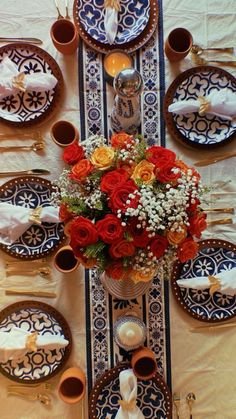 the table is set with plates, silverware and flowers