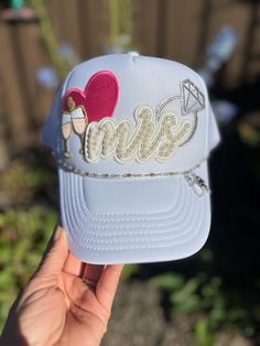 This adorable trucker hat is the perfect gift for a bachelorette or new bride! A white Otto trucker hat includes a pearl "Mrs" patch, a pink heart, champagne flutes and a sparkly diamond ring! A silver and pearl hat chain has the cutest little bride and groom dangling from it. The hat chain is removable if desired. Bride Trucker Hat With Patches, Bridesmaid Trucker Hats, Bride Trucker Hat, Pearl Hat, Hat Chain, Bachelorette Hats, Hat Bar, Marriage Material, New Bride