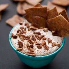 a blue bowl filled with food next to crackers and chips on a black table