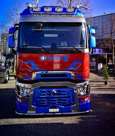 a red and blue truck parked in front of a building