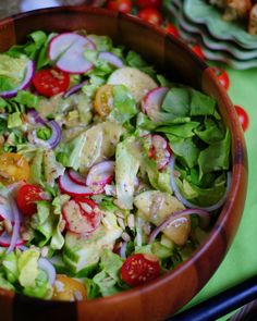 a wooden bowl filled with salad on top of a table