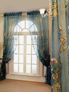 a window with blue curtains and flowers on the windowsill, in front of a chandelier