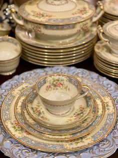 a table topped with lots of plates covered in gold and blue china cups and saucers