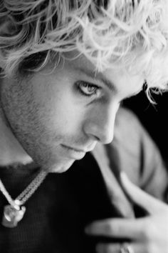 black and white photograph of a young man looking at his cell phone while wearing a necklace