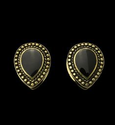 pair of earrings with black stones and gold trimmings on the front, against a black background