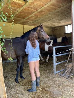 a woman standing next to a horse in a barn