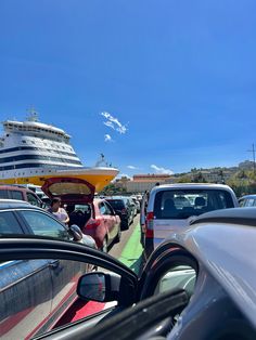 cars are parked on the side of the road with a cruise ship in the background