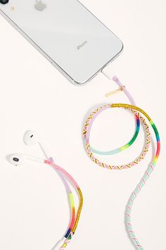 an apple phone and ear buds on a white surface next to each other with colorful cords