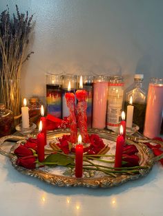 candles are arranged on a tray with roses and other items in front of the candle holders