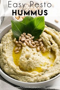 hummus in a white bowl with green leaves on top