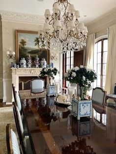 an elegant dining room with chandelier, chairs and table in front of the fireplace