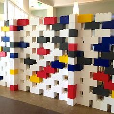 a wall made out of lego blocks with different colors and shapes on it in an office building