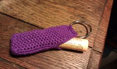 a purple crocheted keychain sitting on top of a wooden table next to a tube of deodorant