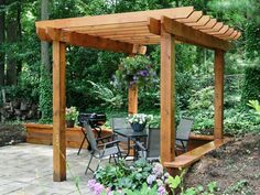 an outdoor dining area in the middle of a garden with lots of plants and flowers