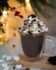 hot chocolate and marshmallows are garnished with whipped cream in a mug