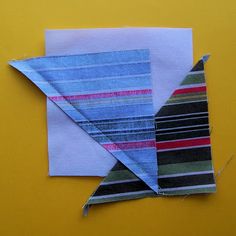 an origami bird made out of strips of fabric on a yellow surface with scissors