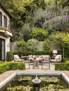 an outdoor dining area with water lilies in the pond and patio furniture around it