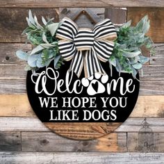 a welcome sign hanging on the side of a wooden wall with succulents