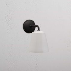 a white light hanging from the side of a wall next to a black and white lamp