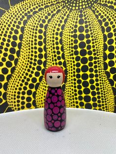 a small figurine sitting on top of a white table next to a yellow and black wall