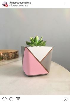 a pink and grey planter sitting on top of a white table next to a piece of wood