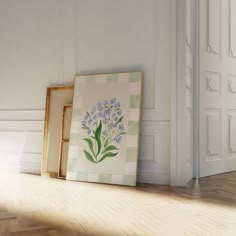 an empty frame sitting on the floor next to a painting