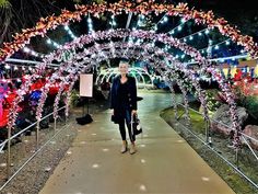 a woman walking down a walkway covered in lights