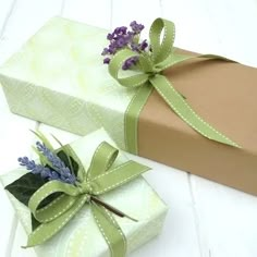 two wrapped gift boxes with green ribbons and lavenders on them, sitting next to each other