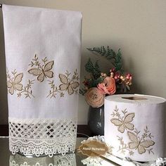 two rolls of toilet paper sitting on top of a table next to a vase with flowers