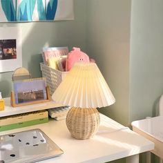 a lamp sitting on top of a white desk next to a laptop and other items