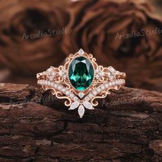 an emerald colored stone surrounded by white diamonds sits on top of a piece of wood