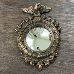 a mirror with an eagle on it sitting on top of a wooden table