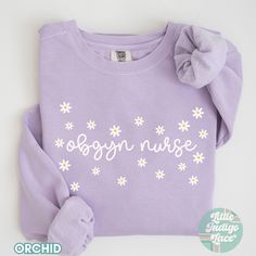 a purple shirt with white daisies and the words organ nurse written on it in cursive writing