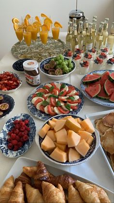 an assortment of fruits and pastries are on display at a buffet table with glasses of orange juice