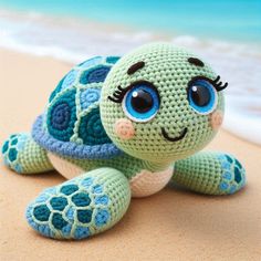 a crocheted turtle sitting on top of a sandy beach