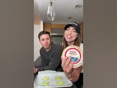 a man and woman sitting at a table with food in front of them, smiling for the camera