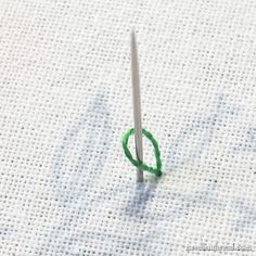 a pair of scissors are sitting on a piece of white fabric next to a needle