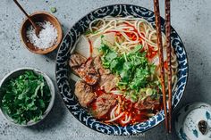 a bowl of beef noodle soup with chopsticks next to it on a table