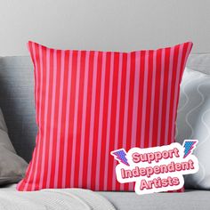 a red and white striped pillow with the words support independent artists in pink on it