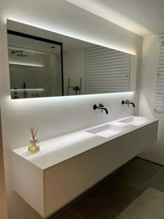 a modern bathroom with two sinks and a large mirror above the sink is illuminated by recessed lighting