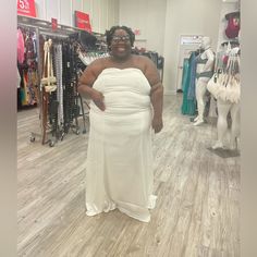 a woman in a white dress standing in a clothing store with her hands on her hips