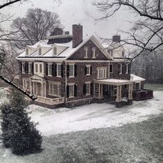 a large brick house with snow on the ground and trees in front of it,