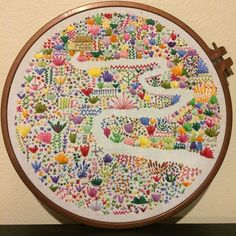 a colorful embroidery is displayed on a wooden frame