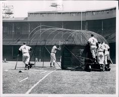 an old black and white photo of baseball players in the batting cage at a stadium