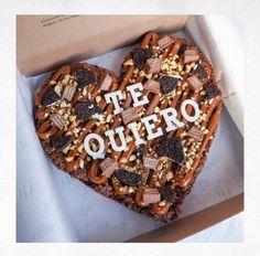 a heart - shaped cookie with the words te quero written on it is in a box