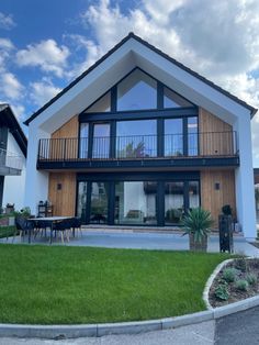 a modern house with large windows and grass in front