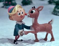 there is a small doll and a deer in the snow with it's nose to each other