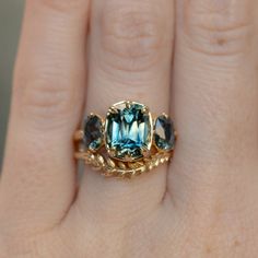 a woman's gold ring with blue topazte and green tourmaline stones